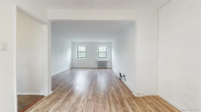 a view of an empty room with wooden floor and window