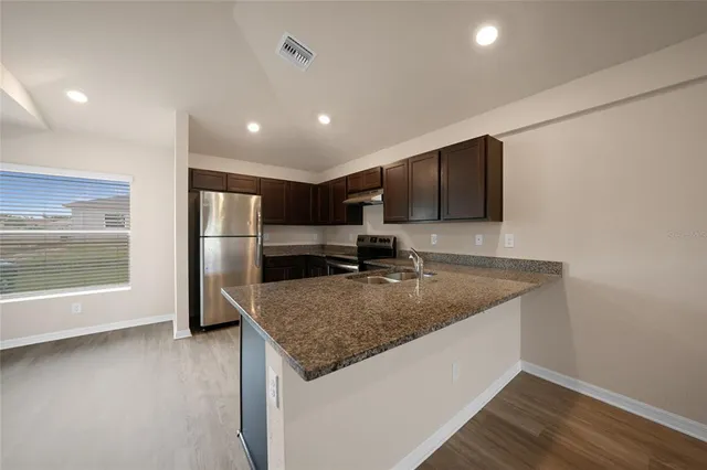 a kitchen with stainless steel appliances granite countertop a sink a refrigerator and a stove top oven