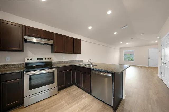 a kitchen with stainless steel appliances granite countertop a stove a sink and a microwave