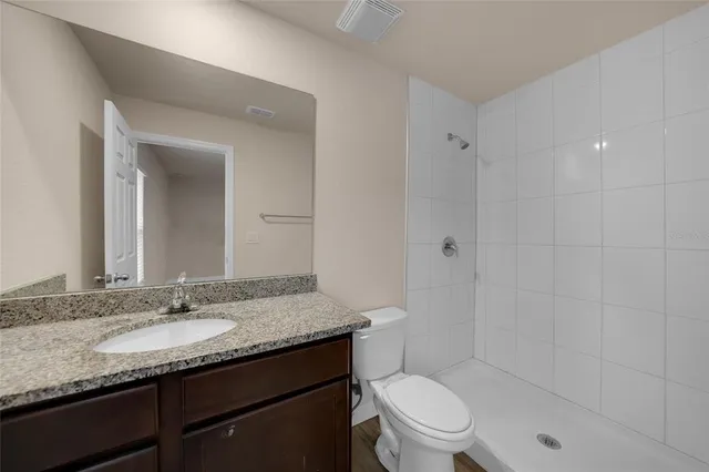 a bathroom with a granite countertop sink toilet and shower