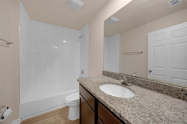 a bathroom with a granite countertop sink toilet and shower