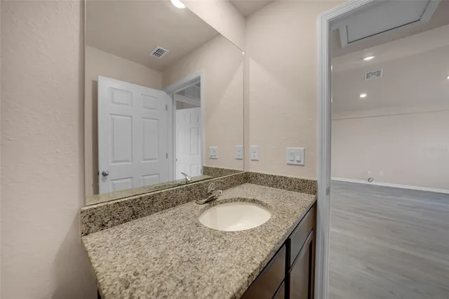 a bathroom with a granite countertop sink and a mirror