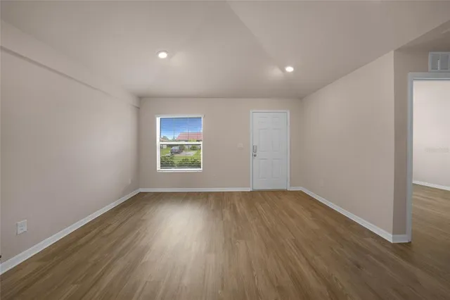 an empty room with wooden floor and windows