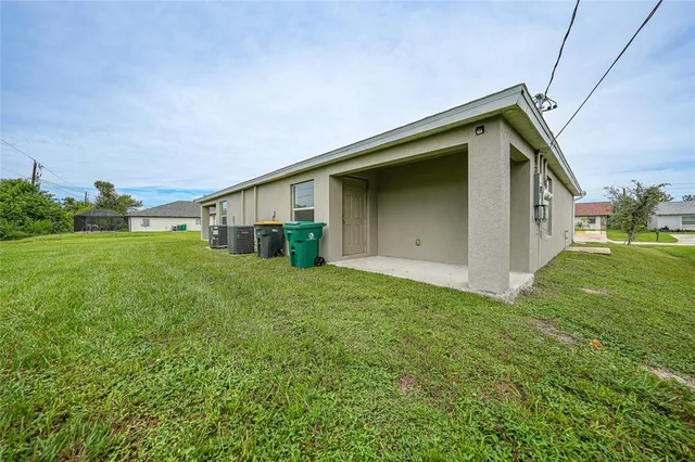 a backyard of a house with plants and large tree