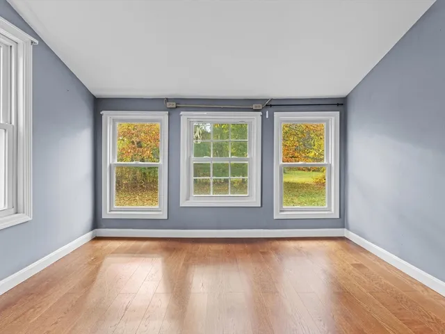 an empty room with a window and wooden floor