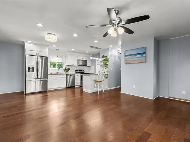 a view of an empty room with kitchen appliances and a ceiling fan