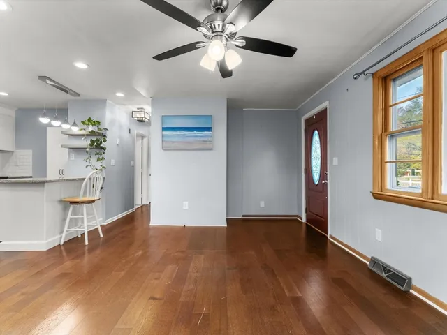 a view of an empty room with window and wooden floor