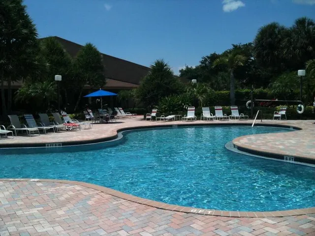 a view of a swimming pool with lawn chairs under an umbrella
