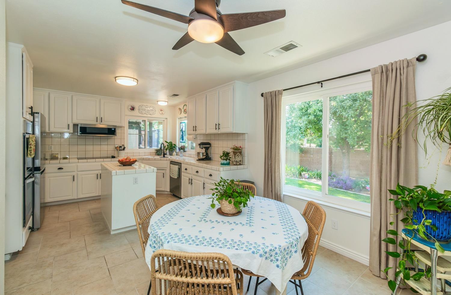 1323 Oak Avenue Clovis, CA 93611 - Photo 12 of 42 a kitchen with stainless steel appliances granite countertop a sink dishwasher a stove a refrigerator with a dining table and chairs with wooden floor