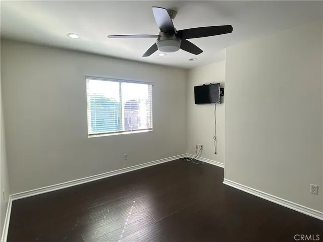an empty room with wooden floor and a ceiling fan