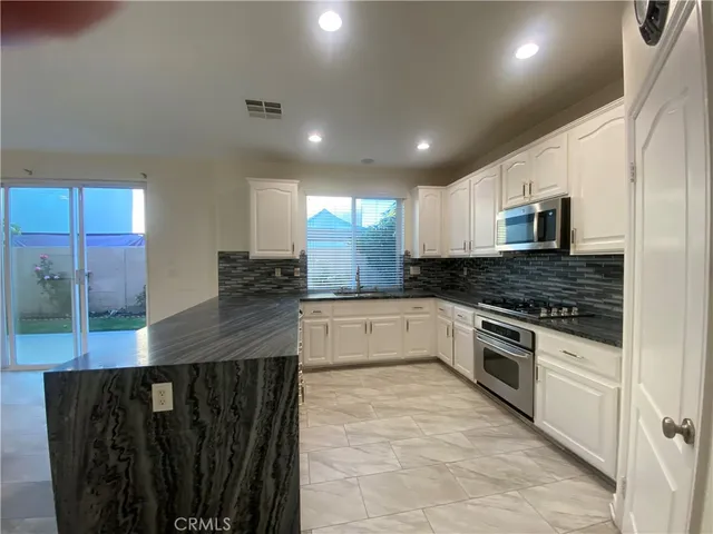 a large kitchen with stainless steel appliances granite countertop a stove a sink and a microwave