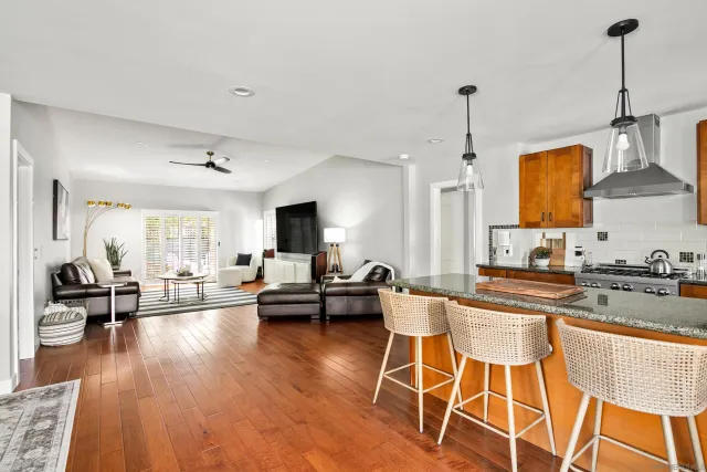 a kitchen with stainless steel appliances granite countertop a stove a sink dishwasher and a dining table with wooden floor