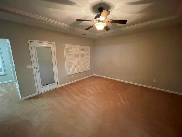 an empty room with a ceiling fan and window