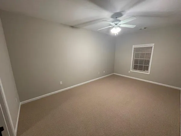 an empty room with windows and chandelier fan
