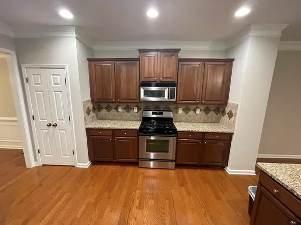 a kitchen with granite countertop a refrigerator stove top oven and sink