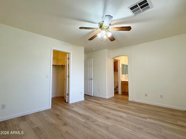 an empty room with wooden floor closet and windows