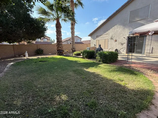 a backyard of a house with table and chairs plants and large tree
