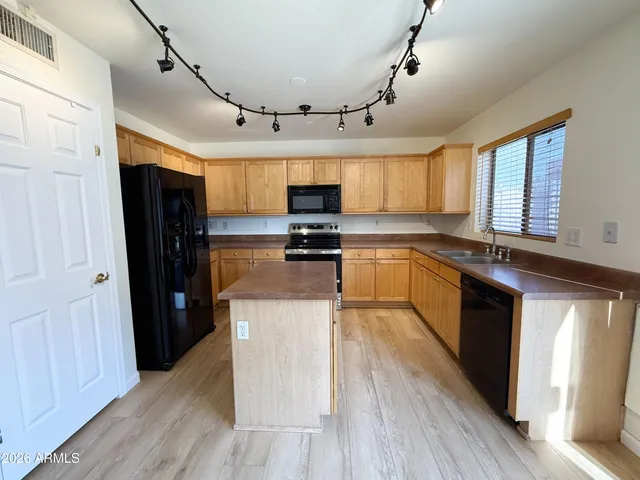 a kitchen with granite countertop a refrigerator a sink dishwasher a stove and white cabinets with wooden floor