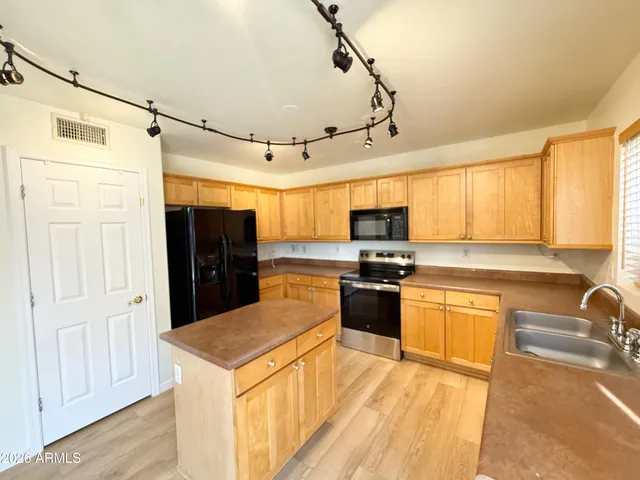 a kitchen with stainless steel appliances granite countertop a refrigerator a sink dishwasher a stove and white cabinets with wooden floor