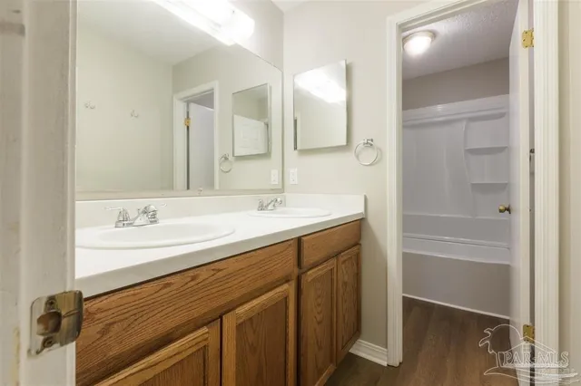 a bathroom with a double vanity sink a mirror and a bathtub