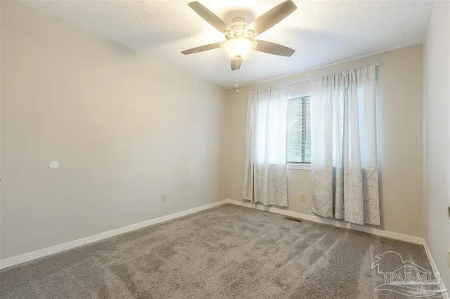 an empty room with windows and fan