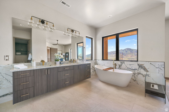 10646 North Reflection Ridge Hideout, UT 84036 - Photo 32 of 43 Spacious bathroom featuring a free-standing soaking tub, large windows with mountain scenery, dual vanity with extensive countertop space, full-width mirror, and large format floor tiling