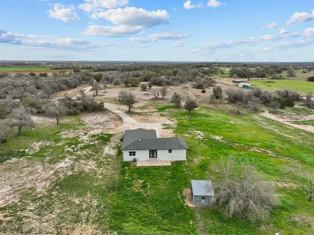 an aerial view of residential houses with outdoor space and trees