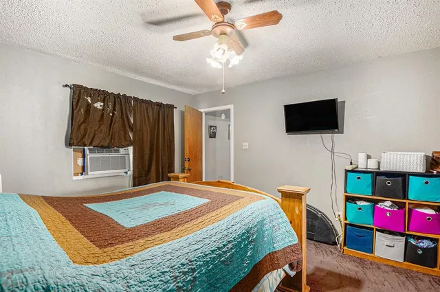 a bedroom with a bed a flat screen tv and a chandelier