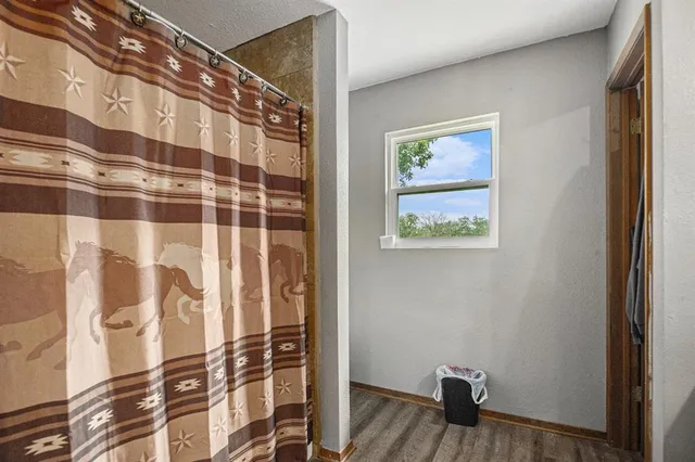 a view of a hallway with wooden floor and a bathroom