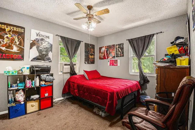 a bedroom with a bed a standing fan and a window