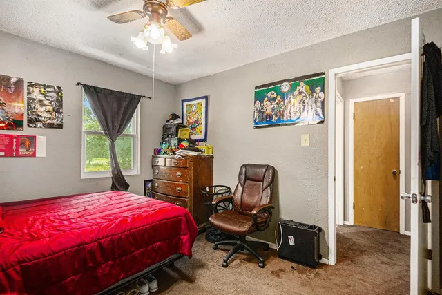 a bedroom with a bed a computer on desk and a dresser next to a window