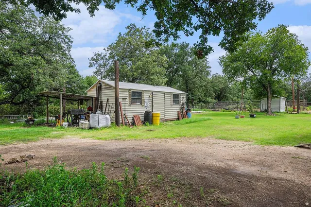 a view of a house with a yard and large trees