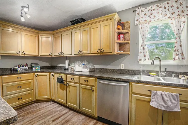 a kitchen with stainless steel appliances granite countertop a sink a stove cabinets and wooden floor