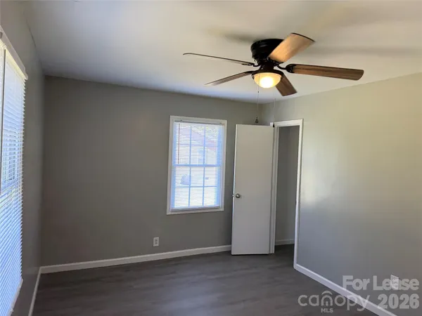 a view of an empty room with window and wooden floor
