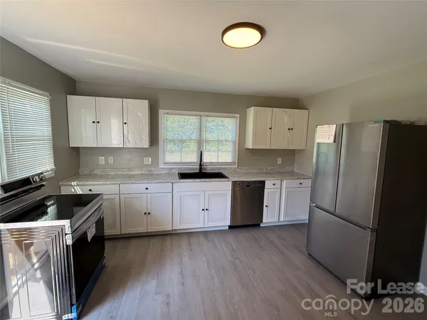 a kitchen with granite countertop a refrigerator stove top oven and sink
