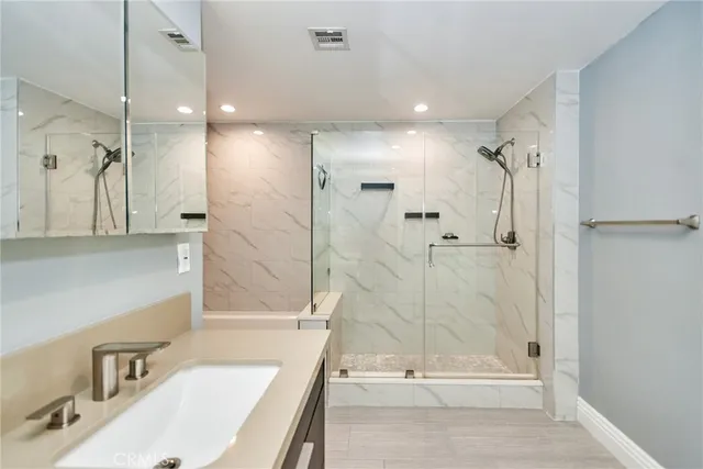 a bathroom with a tub shower sink and mirror