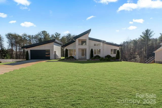 a front view of house with yard and trees in the background
