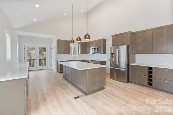 a large kitchen with kitchen island a large counter top a sink a center island stainless steel appliances and cabinets
