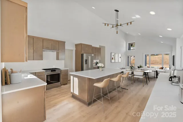 a kitchen with stainless steel appliances granite countertop a stove oven a sink dishwasher a dining table and chairs with wooden floor