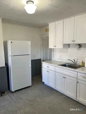 a kitchen with refrigerator and white cabinets