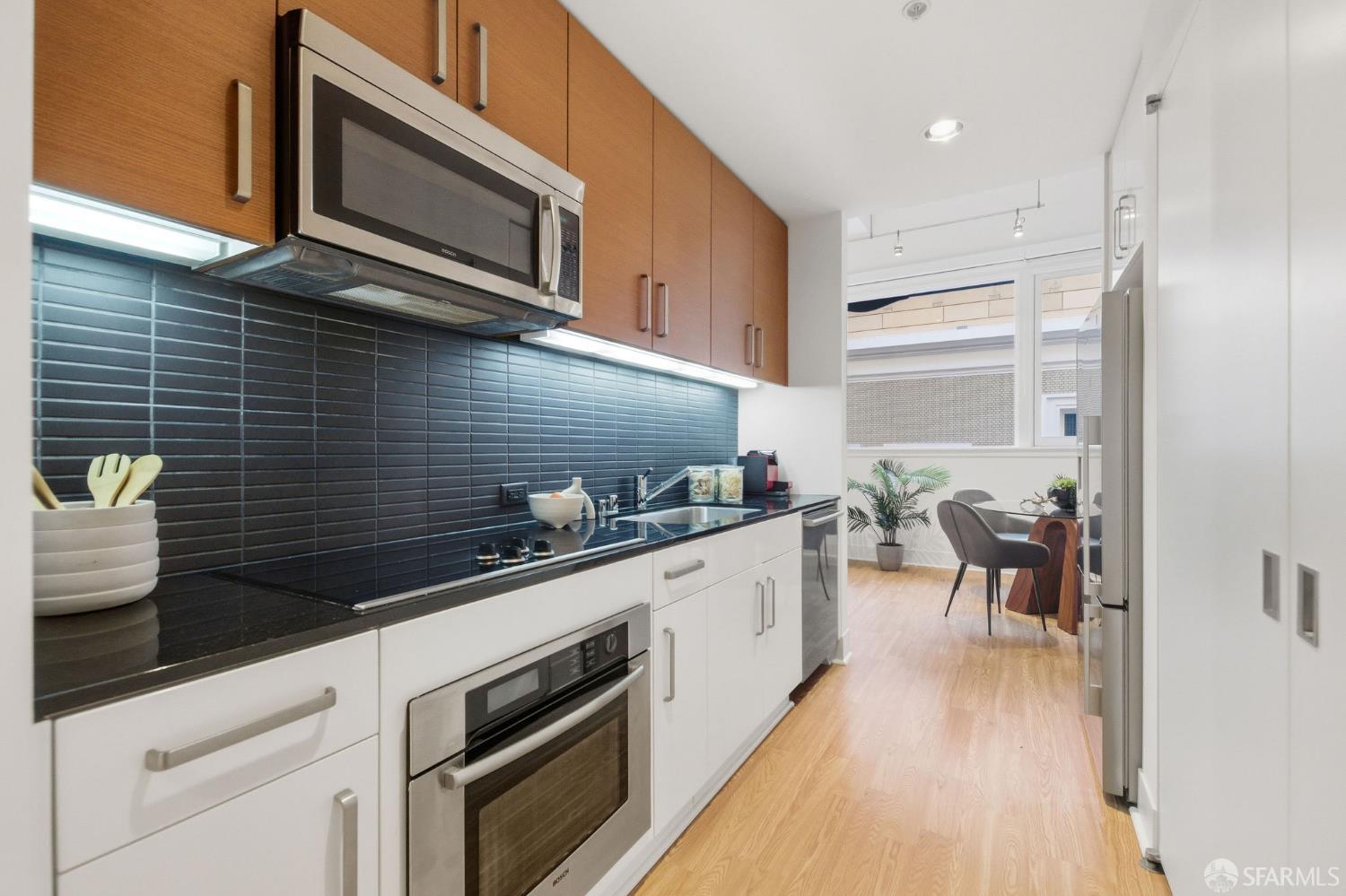 74 New Montgomery Street, Unit 211 San Francisco, CA 94105 - Photo 5 of 22 a kitchen with stainless steel appliances kitchen island granite countertop a stove a sink and white cabinets