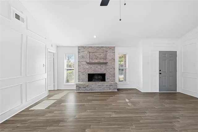 a view of an empty room with wooden floor fireplace and a window