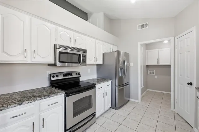 a kitchen with stainless steel appliances granite countertop a refrigerator and a stove top oven