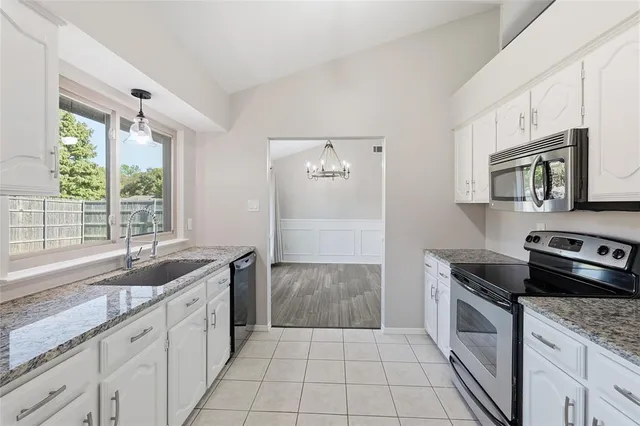 a kitchen with granite countertop a sink stove and cabinets