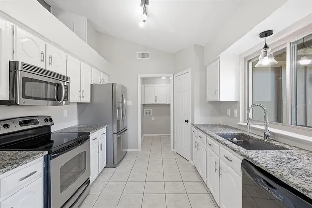 a kitchen with stainless steel appliances granite countertop a sink stove microwave and refrigerator