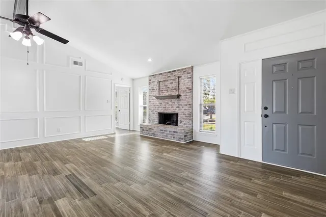 an empty room with wooden floor fireplace and windows