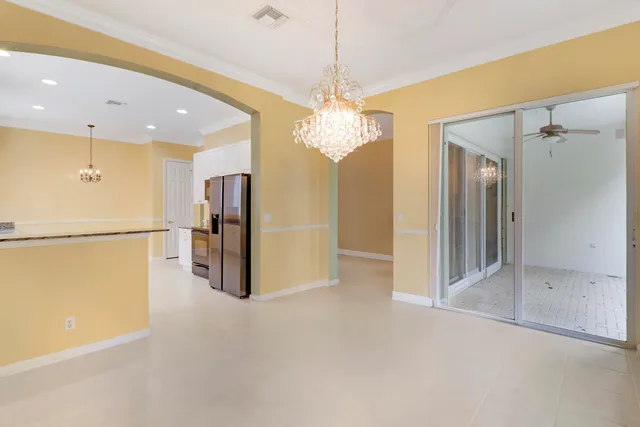a view of a hallway with stainless steel appliances a refrigerator a fireplace and a chandelier