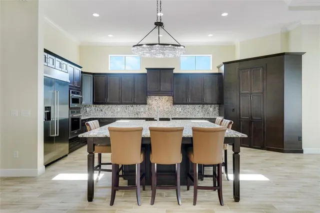 a kitchen with stainless steel appliances granite countertop a dining table chairs sink and cabinets