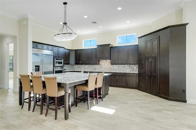 a kitchen with stainless steel appliances kitchen island granite countertop a refrigerator a stove a sink a dining table and chairs