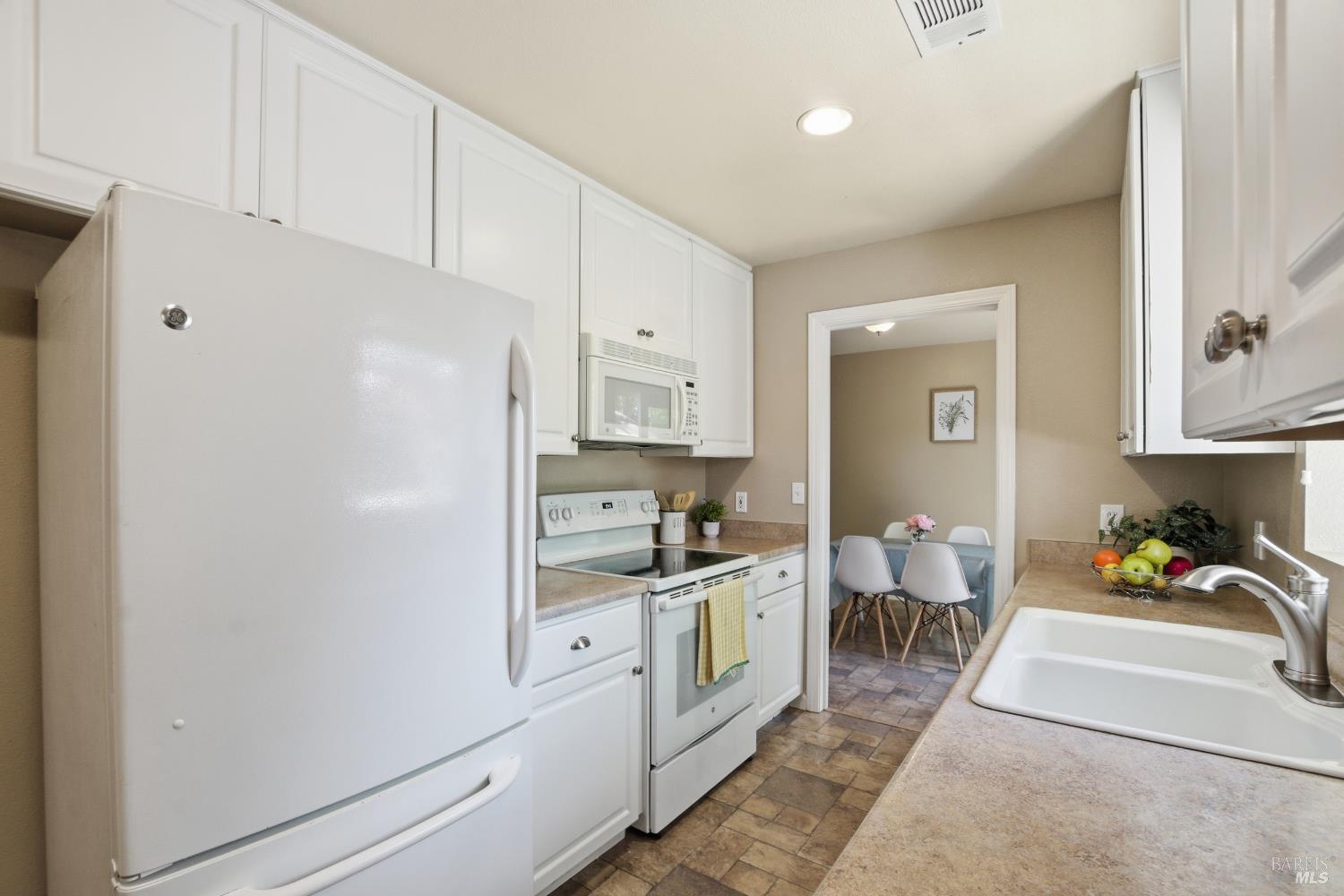 2015 Locust Street Napa, CA 94559 - Photo 28 of 54 a room with stainless steel appliances kitchen island granite countertop a refrigerator a sink a stove and white cabinets